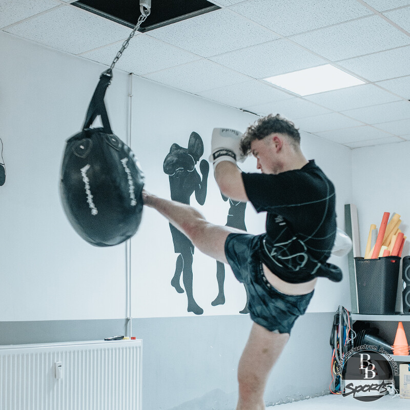 Kickboxer beim Highkick Training mit ovalem Boxsack